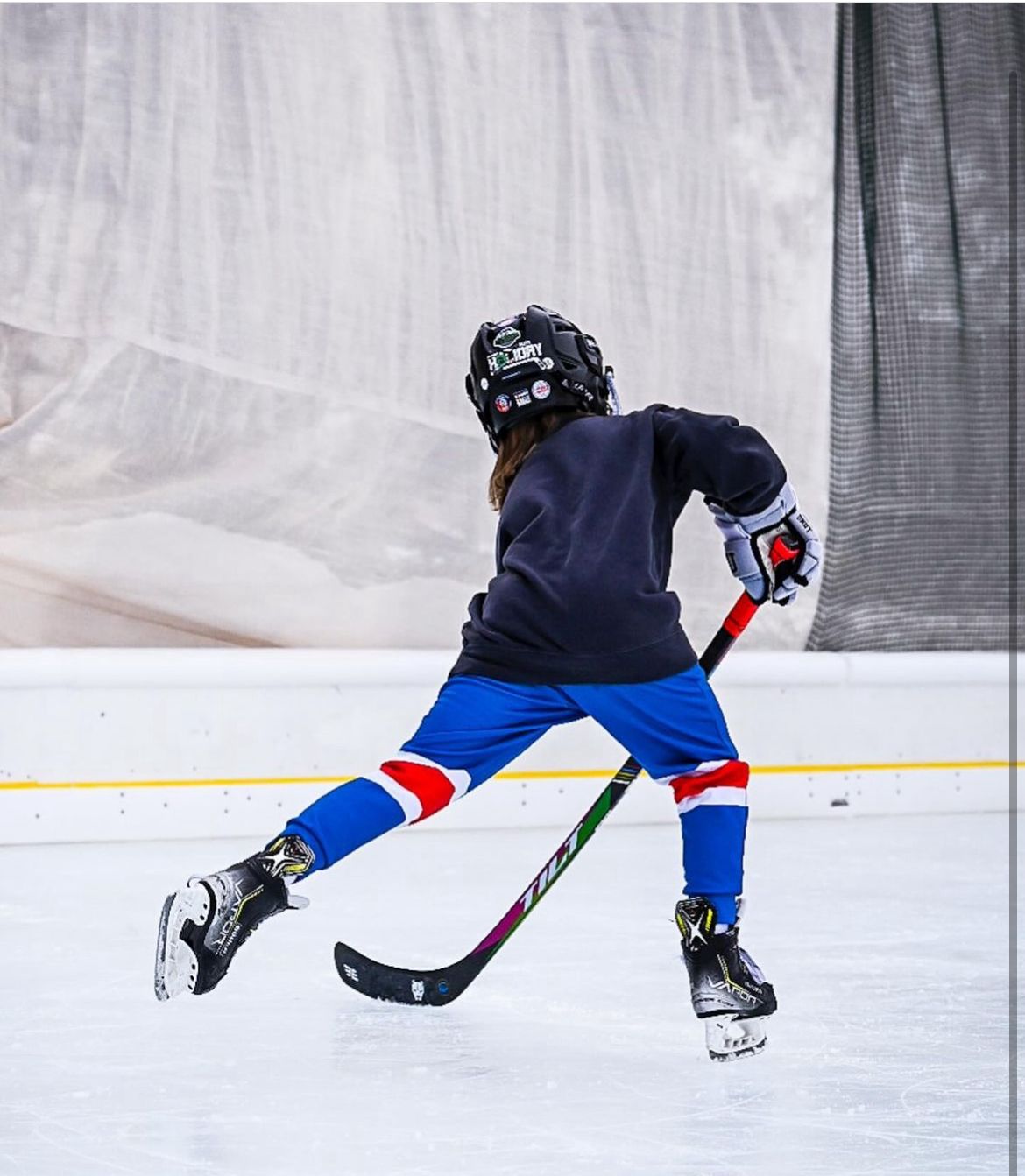 Youth player mid-stride with colorful Tilt stick on the ice