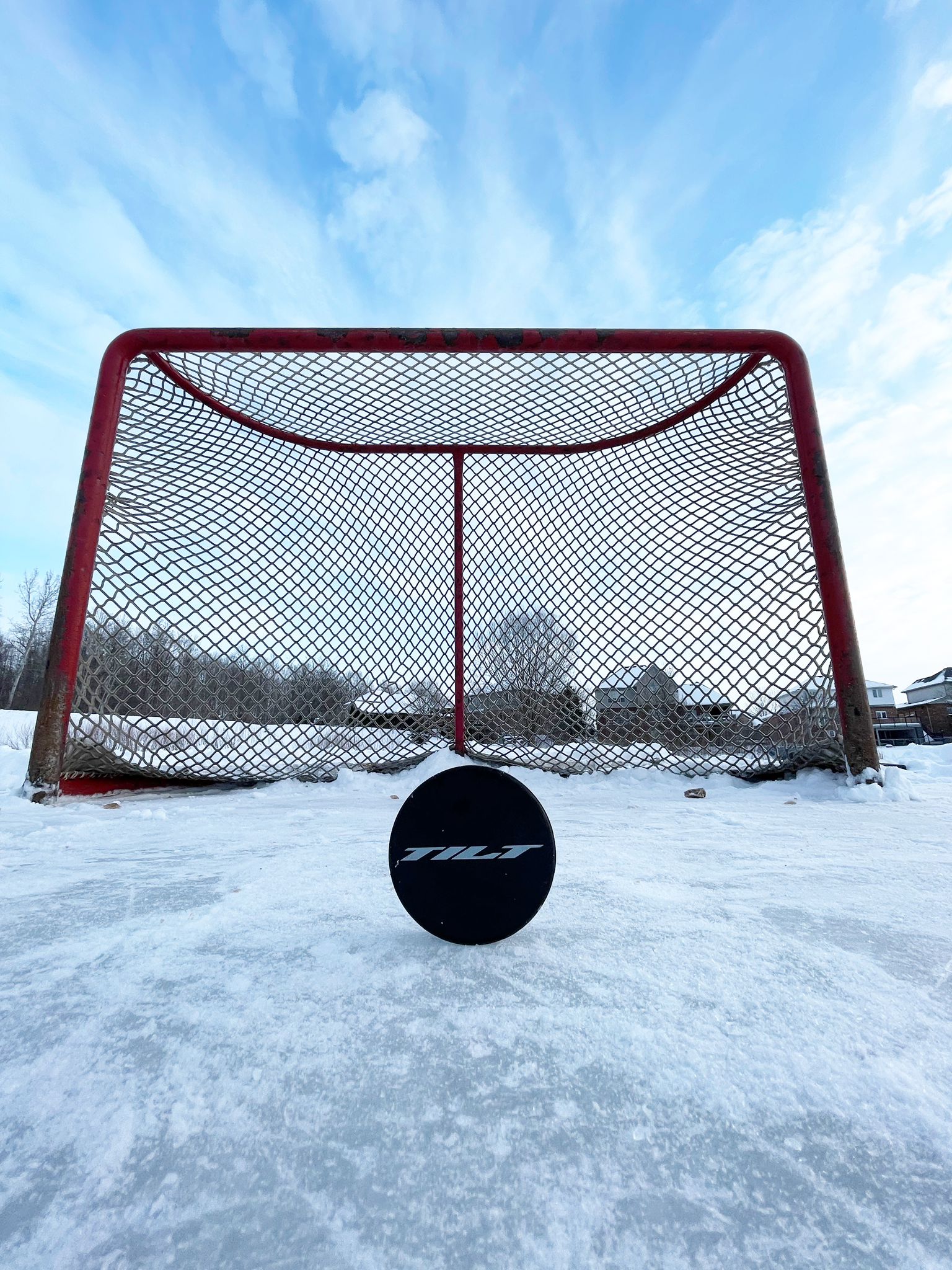 Tilt Hockey puck on outdoor ice in front of a net on a winter day