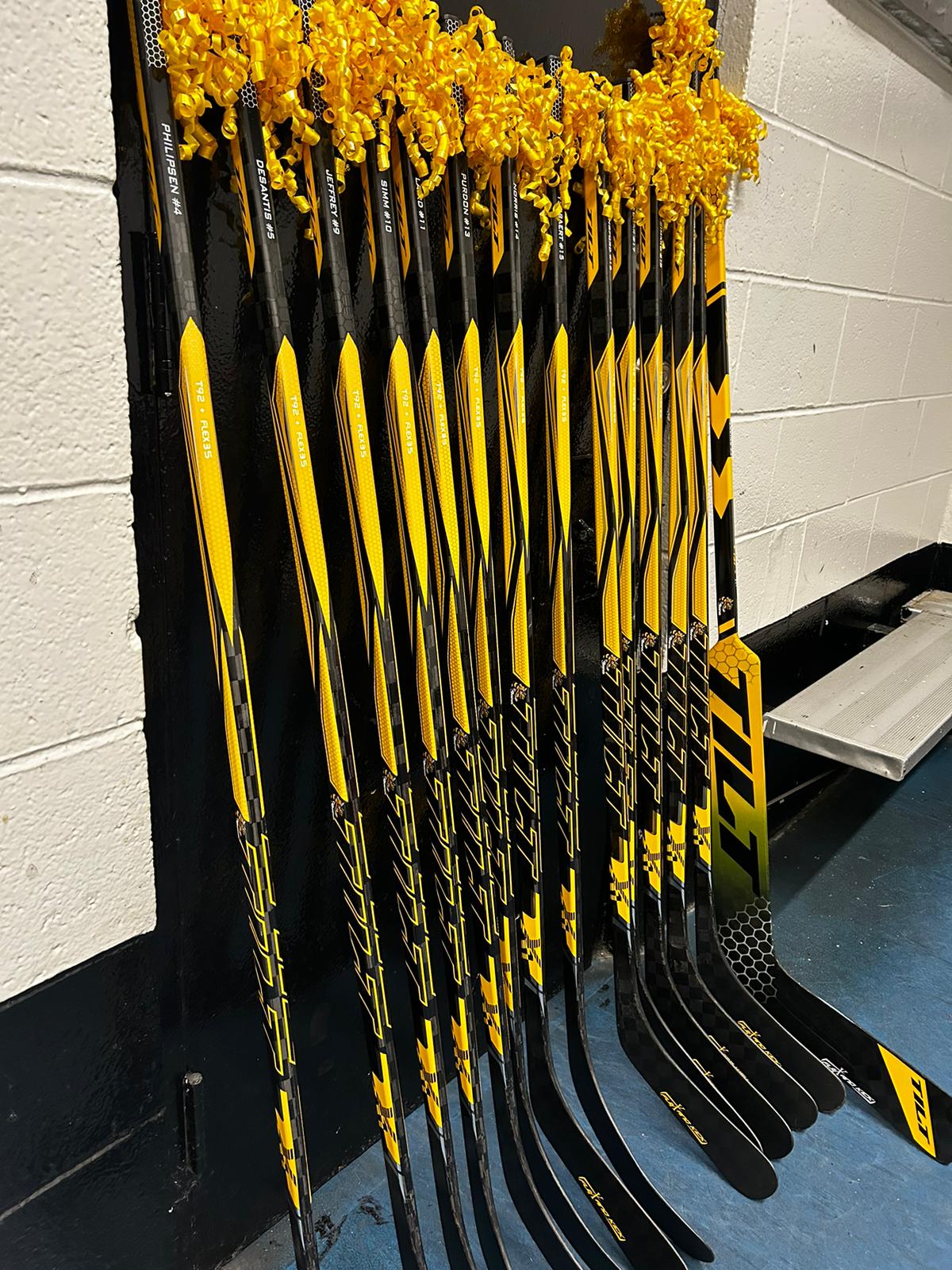 Custom Tilt team sticks with player names in locker room rack